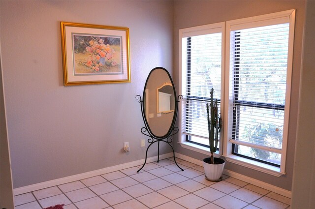 bedroom featuring baseboards, a ceiling fan, ensuite bath, a fireplace, and light tile patterned flooring