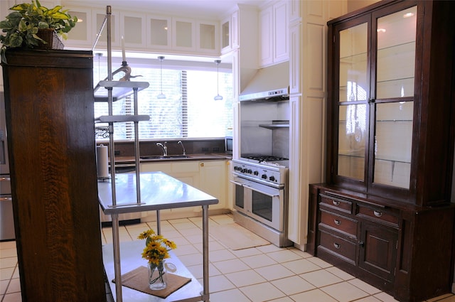 kitchen featuring light tile patterned floors, white cabinets, decorative light fixtures, sink, and range with two ovens