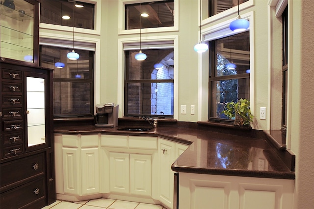 kitchen with sink, white cabinetry, light tile patterned floors, and decorative light fixtures