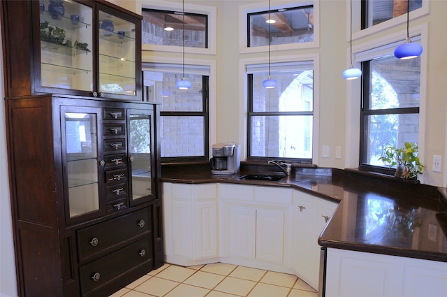 kitchen with sink, white cabinets, pendant lighting, and light tile patterned floors