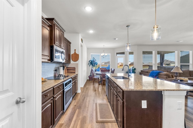 kitchen featuring sink, stainless steel appliances, light hardwood / wood-style flooring, decorative light fixtures, and dark brown cabinets