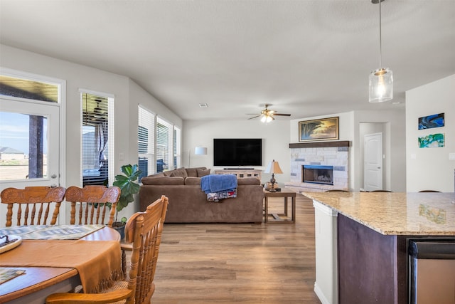 dining space featuring a fireplace, ceiling fan, and light hardwood / wood-style floors