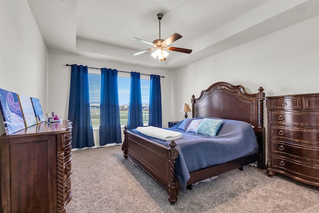 carpeted bedroom featuring ceiling fan and a raised ceiling