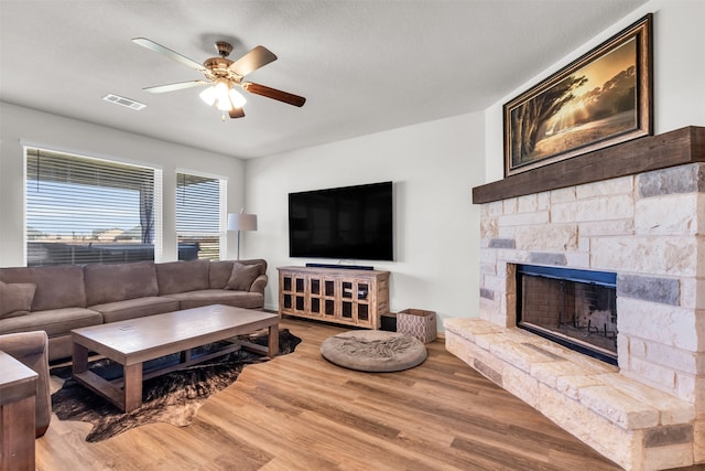 living room with a fireplace, a textured ceiling, hardwood / wood-style flooring, and ceiling fan