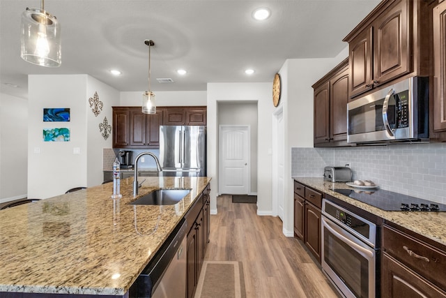 kitchen featuring dark brown cabinets, an island with sink, stainless steel appliances, and sink