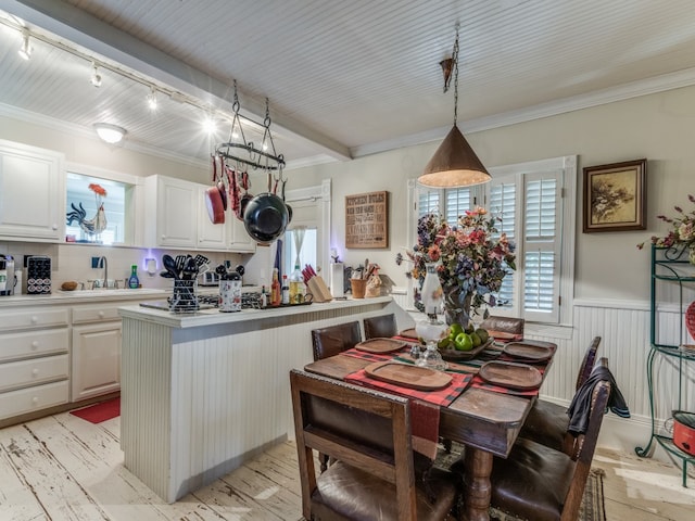 kitchen with pendant lighting, ornamental molding, a kitchen island, rail lighting, and white cabinetry