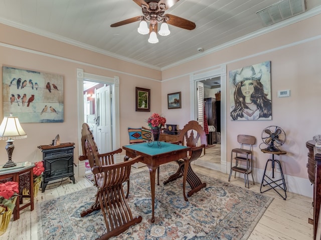 dining room with a wood stove, wooden ceiling, crown molding, ceiling fan, and light hardwood / wood-style flooring