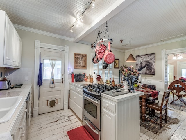 kitchen with hanging light fixtures, light hardwood / wood-style floors, gas range, and white cabinets