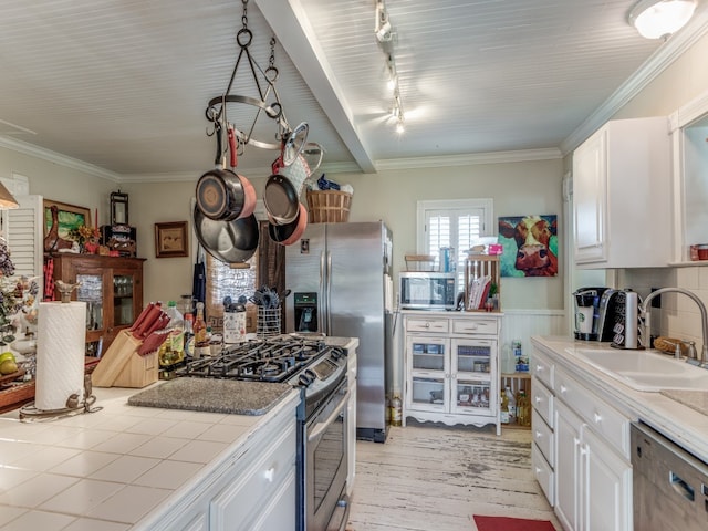 kitchen with tile counters, sink, white cabinetry, rail lighting, and appliances with stainless steel finishes