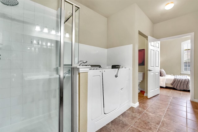 bathroom featuring toilet, a shower with shower door, and tile patterned flooring