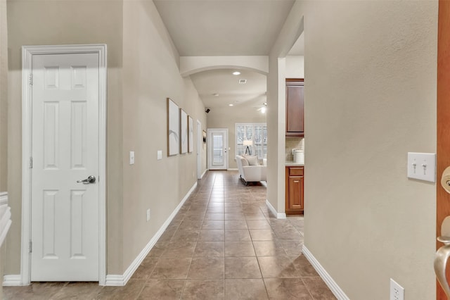 hallway featuring lofted ceiling and light tile patterned flooring