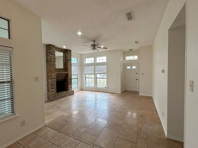 unfurnished living room with ceiling fan, a textured ceiling, and a brick fireplace