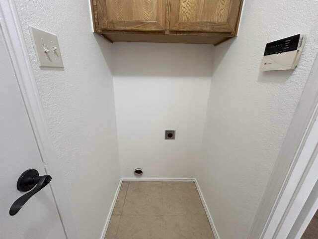 laundry room featuring cabinets, electric dryer hookup, and light tile patterned floors