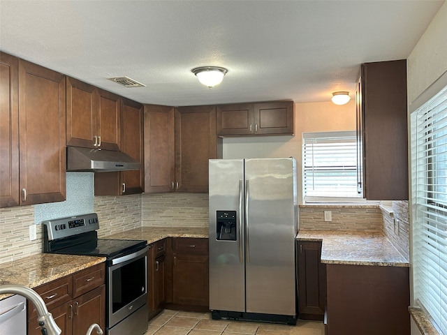 kitchen with light stone counters, appliances with stainless steel finishes, and tasteful backsplash