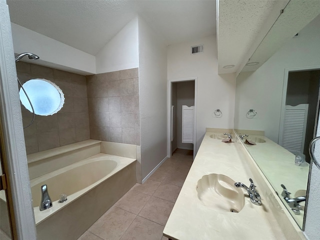 bathroom featuring vanity, tile patterned floors, a textured ceiling, and a tub