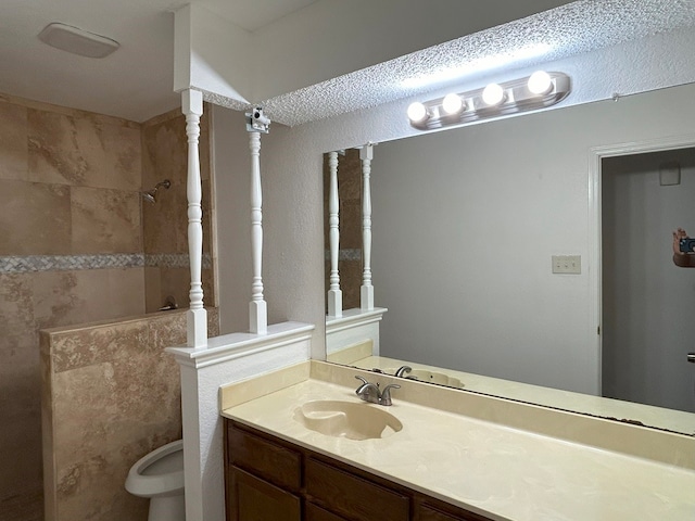 bathroom featuring tiled shower, vanity, and toilet