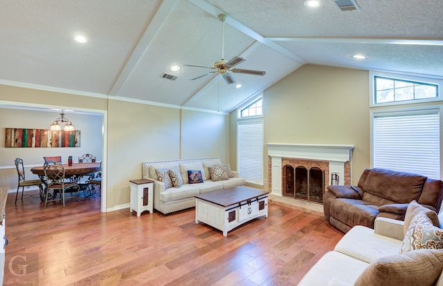 living room featuring ceiling fan, lofted ceiling, a textured ceiling, a fireplace, and hardwood / wood-style floors