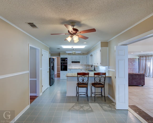 kitchen with white cabinets, ornamental molding, kitchen peninsula, stainless steel appliances, and a breakfast bar