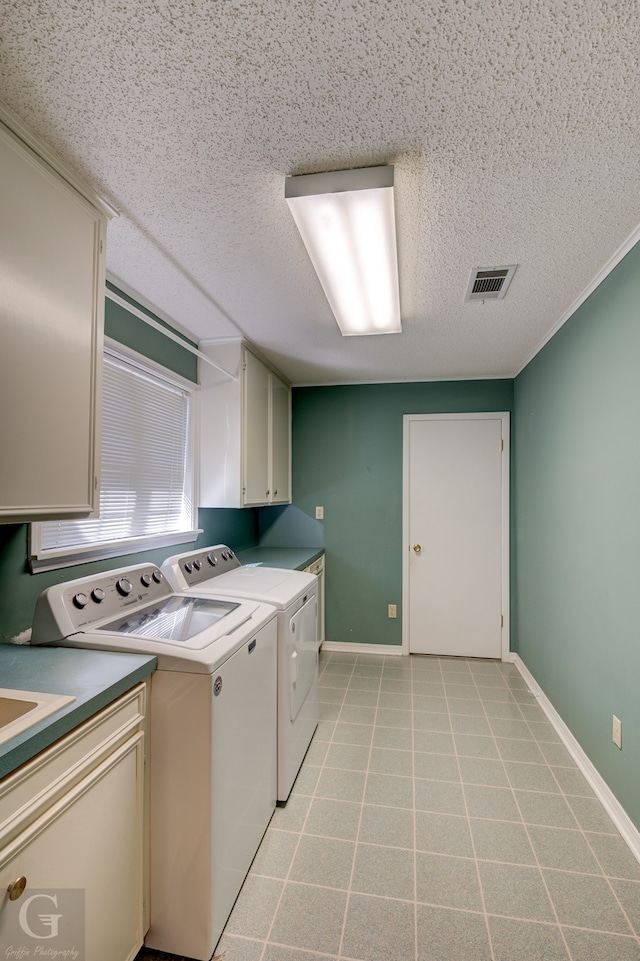 washroom with cabinets, a textured ceiling, and independent washer and dryer