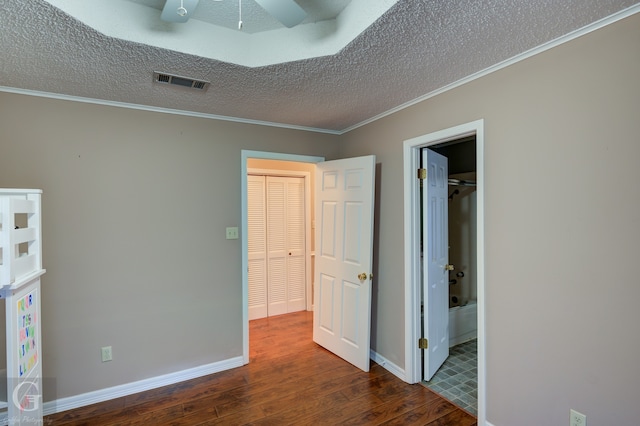 unfurnished bedroom with ceiling fan, a textured ceiling, dark wood-type flooring, a closet, and crown molding