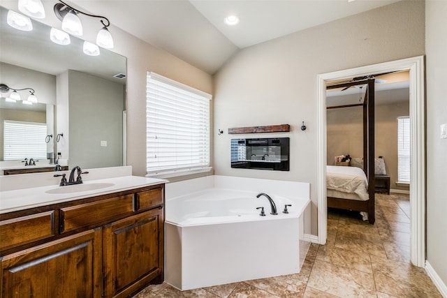 bathroom with vaulted ceiling, tile patterned flooring, a bathtub, and vanity