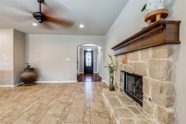 entryway featuring ceiling fan, a stone fireplace, and a textured ceiling