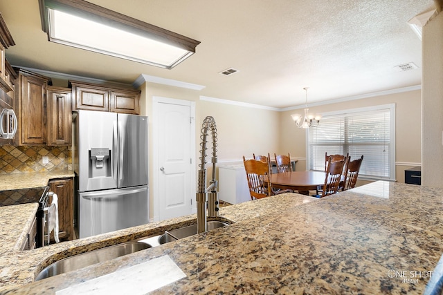 kitchen with a notable chandelier, stainless steel appliances, crown molding, and tasteful backsplash