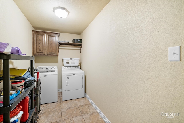 clothes washing area featuring light tile patterned floors, cabinets, and washer and dryer