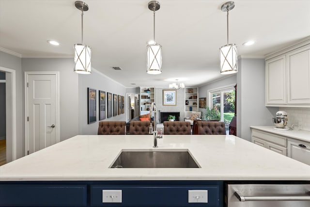 kitchen featuring blue cabinets, ornamental molding, sink, and a large fireplace