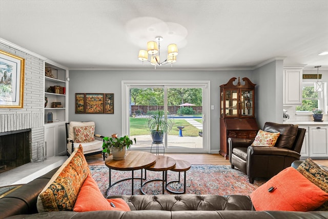 living room with a chandelier, built in shelves, light hardwood / wood-style flooring, a brick fireplace, and crown molding