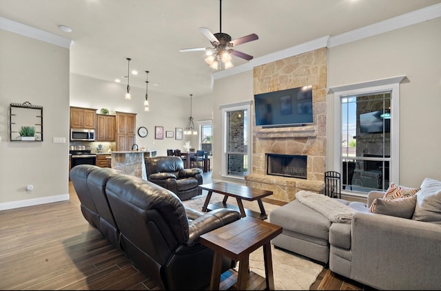 living room featuring a stone fireplace, crown molding, plenty of natural light, and light hardwood / wood-style flooring