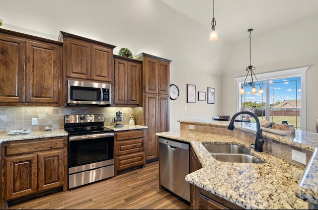 kitchen with appliances with stainless steel finishes, sink, pendant lighting, a notable chandelier, and dark hardwood / wood-style floors