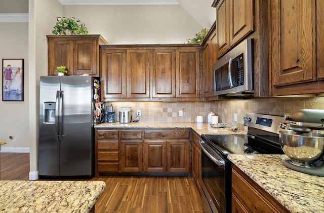 kitchen featuring light stone counters, ornamental molding, backsplash, and appliances with stainless steel finishes