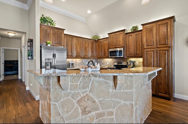 kitchen featuring a kitchen bar, a center island with sink, stainless steel appliances, and dark hardwood / wood-style floors