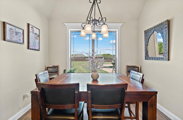 dining space featuring lofted ceiling, wood-type flooring, and an inviting chandelier