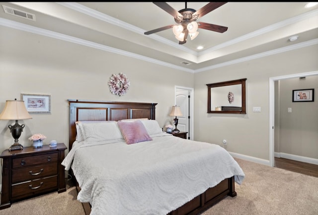 carpeted bedroom featuring a tray ceiling, ceiling fan, and crown molding