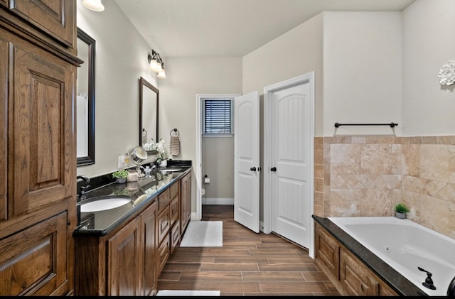 bathroom with a bath, hardwood / wood-style floors, vanity, and toilet