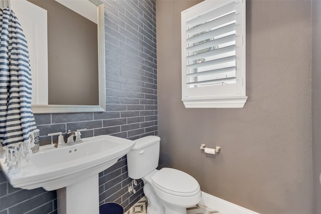 bathroom with decorative backsplash and toilet