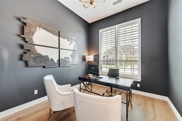 office area with an inviting chandelier, a healthy amount of sunlight, and wood-type flooring