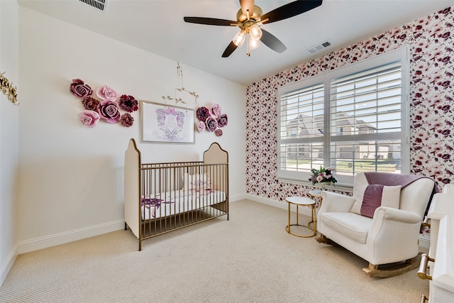 bedroom with carpet flooring, ceiling fan, and a crib