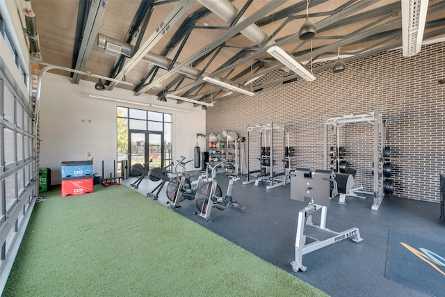 workout area with high vaulted ceiling and brick wall