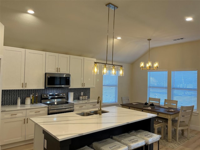 kitchen featuring white cabinetry, sink, stainless steel appliances, and an island with sink