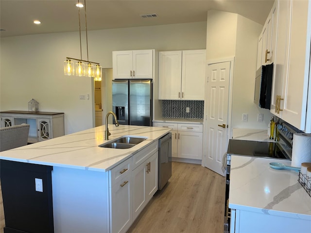 kitchen with stainless steel appliances, white cabinetry, sink, and an island with sink