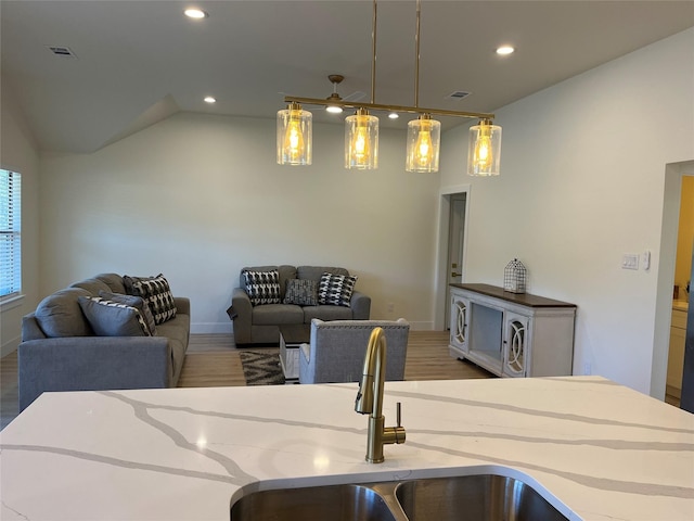 kitchen featuring pendant lighting, sink, hardwood / wood-style flooring, and lofted ceiling