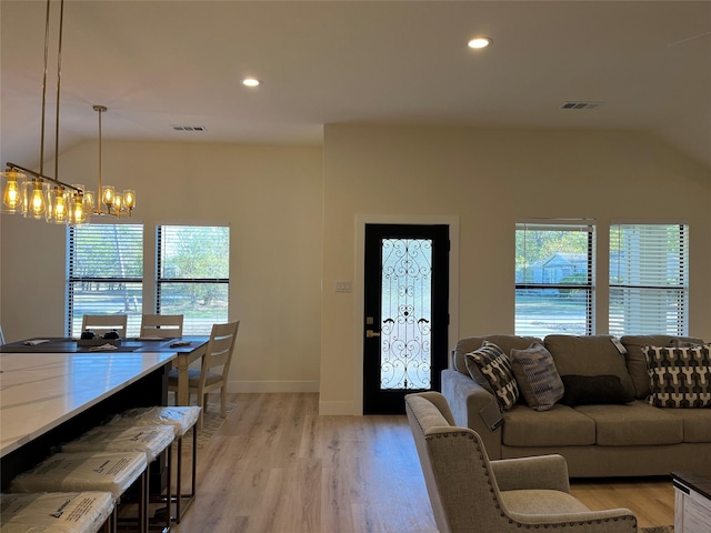 living room featuring lofted ceiling, a notable chandelier, and light hardwood / wood-style flooring