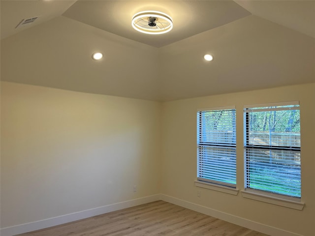 spare room featuring lofted ceiling and light wood-type flooring