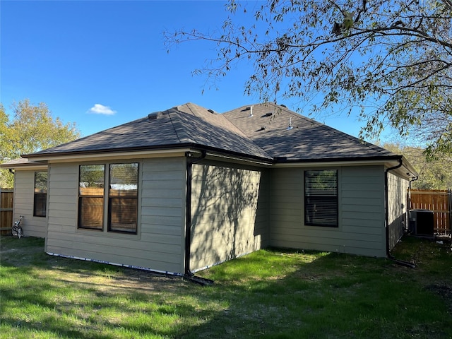 back of property with central AC and a lawn