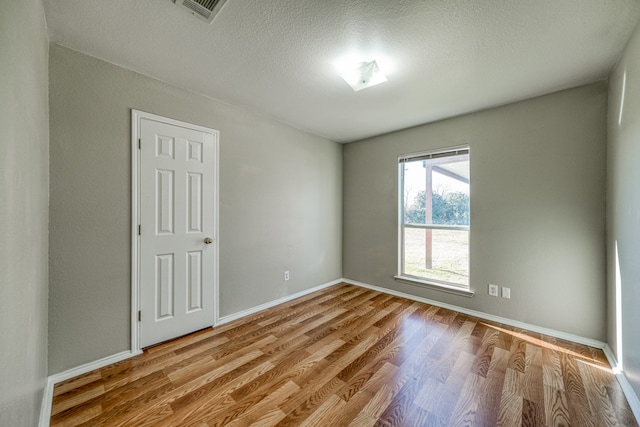 unfurnished room with a textured ceiling and light hardwood / wood-style floors