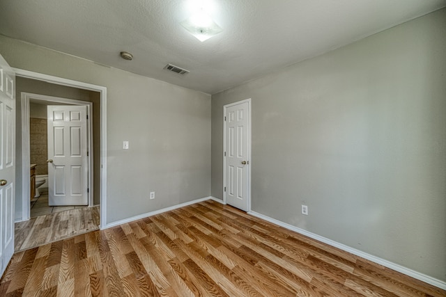 unfurnished bedroom with a textured ceiling and light hardwood / wood-style floors