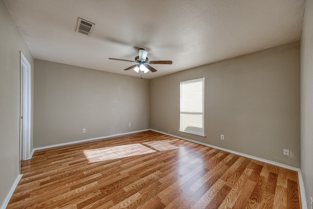 empty room featuring light hardwood / wood-style flooring, ceiling fan, and a textured ceiling